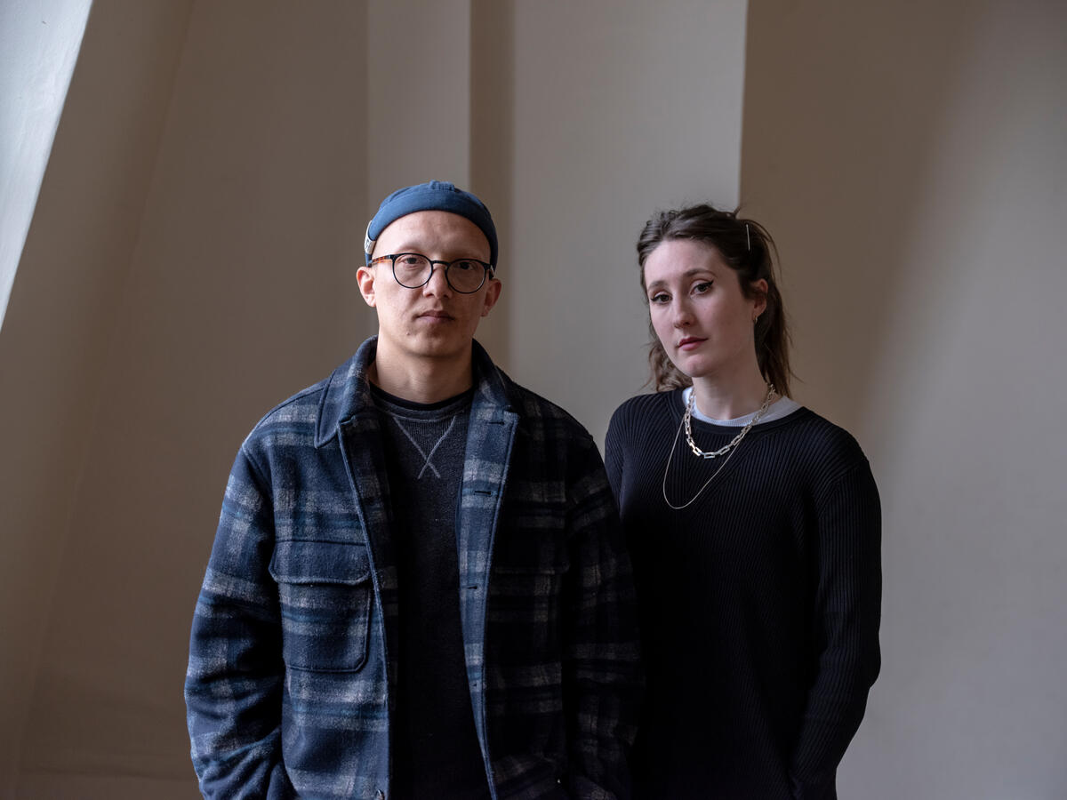 A man and a woman stand facing the camera