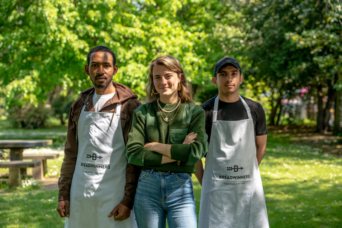 two men and a woman stand together facing the camera in a park