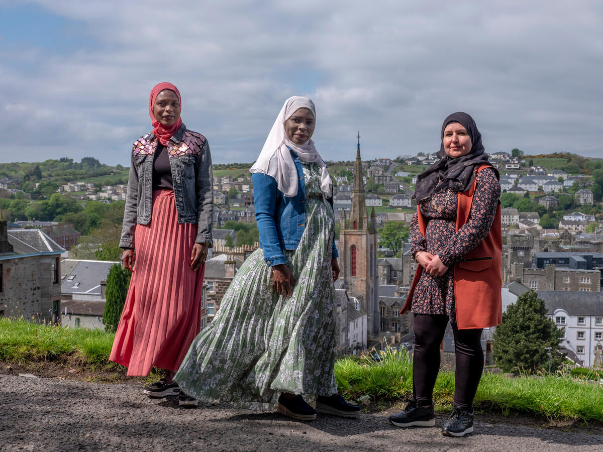 Three women pose outside against a rural backdrop