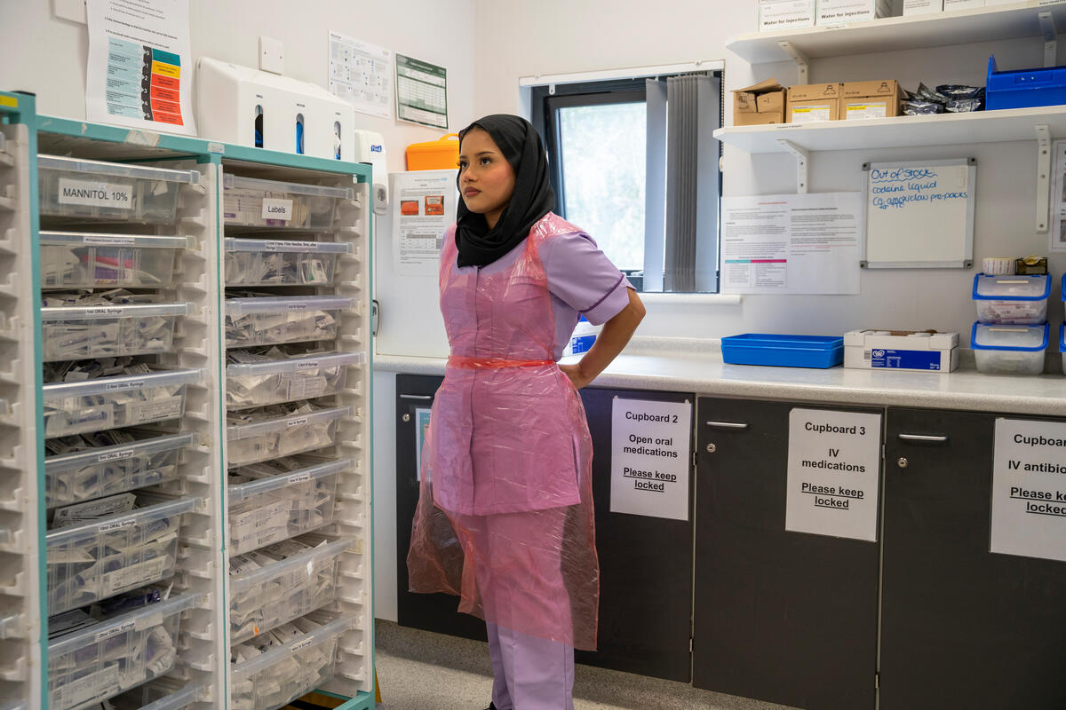 a woman in a nurses uniform in a hospital puts on a pink apron