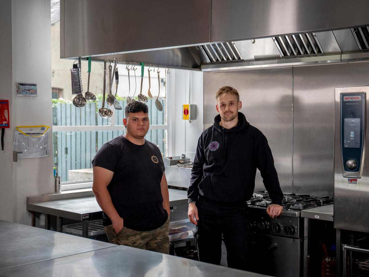 Two men pose in a commercial kitchen