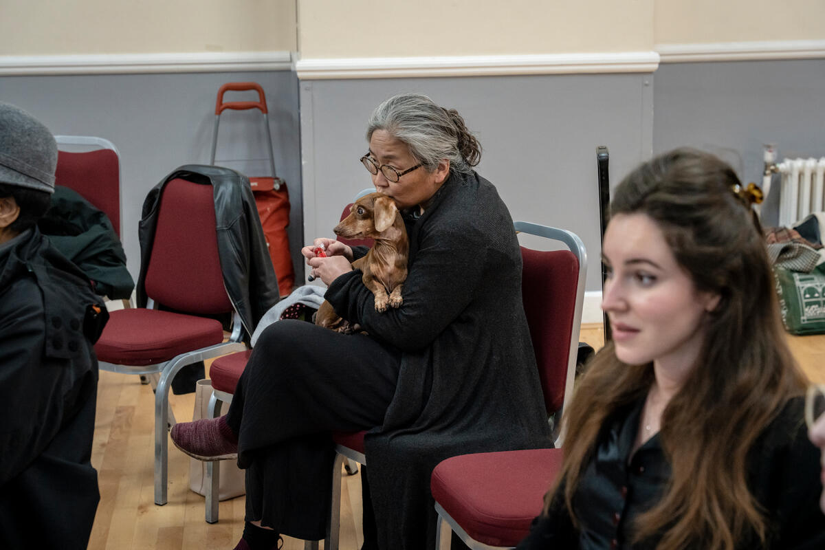 A woman sits with her dog on her lap.