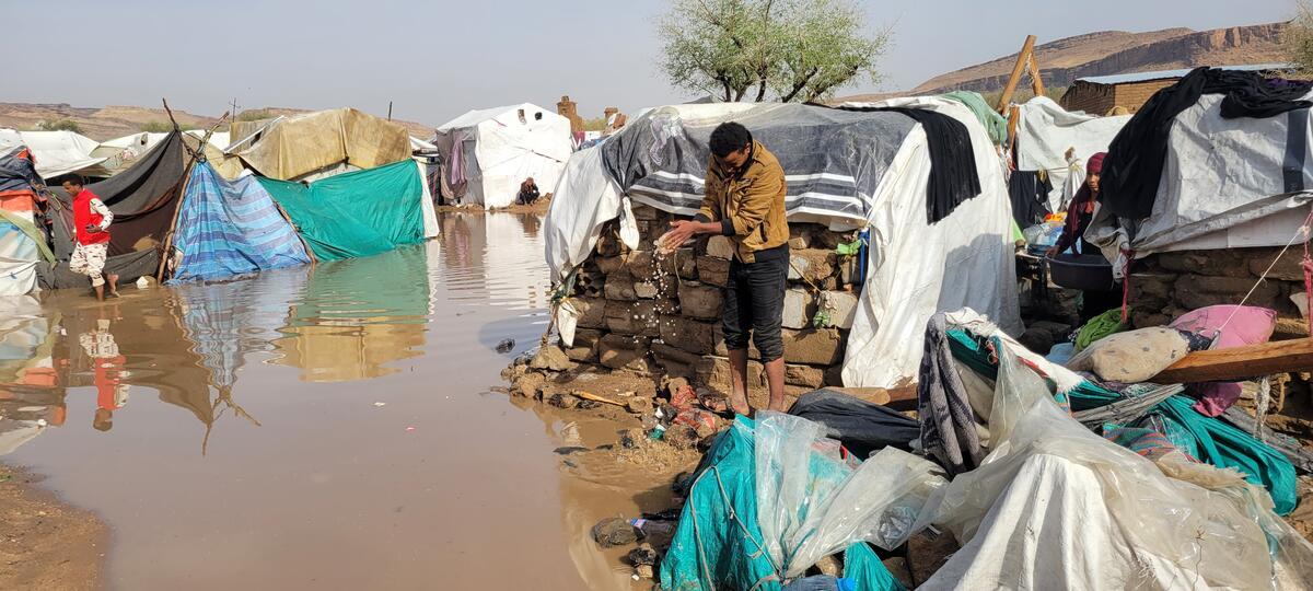 Flooding surrounds shelters and people's belongings at an IDP site.