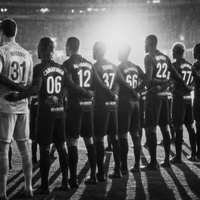 AI-assisted rearview image of a football team lined up on the pitch inside a brightly lit stadium 