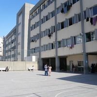 A view of a playground and school building with laundry hanging on lines out of the windows
