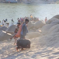 Ethiopian refugees flee across a river with their belongings.