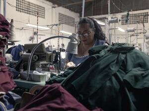 A woman in a factory works at a sewing machine.