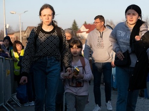 A woman and her daughters walk across the border between Ukraine and Poland carrying their belongings.