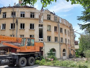 A crane is parked in front of a partially destroyed residential building in Ukraine 