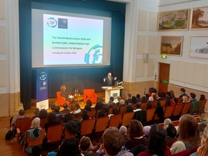 A man gestures as he speaks to an audience from a stage