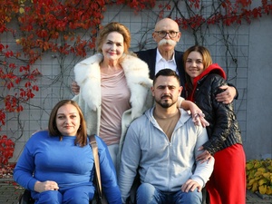 Five people pose for a group photo in front of a plant-covered wall.