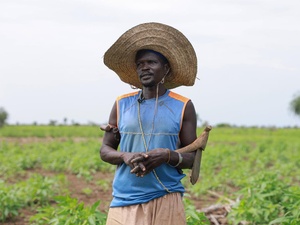  A man wearing a large, straw hat stands in a field.