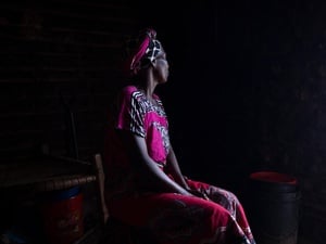 Portrait of a woman with her face turned away against a dark background.