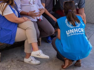 Two UNHCR staff members speak with asylum-seekers in a border town in northern Mexico.