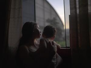 Yenifer está de pie con su hijo de 1 año junto a la ventana de la habitación en la que vive con su pareja a una hora de Lima, Perú. Llegaron a Perú en noviembre de 2019 desde Valencia, Venezuela.