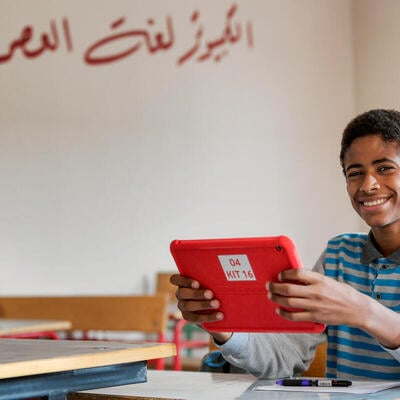 A boy holding a tablet smiles for the camera in Egypt. 