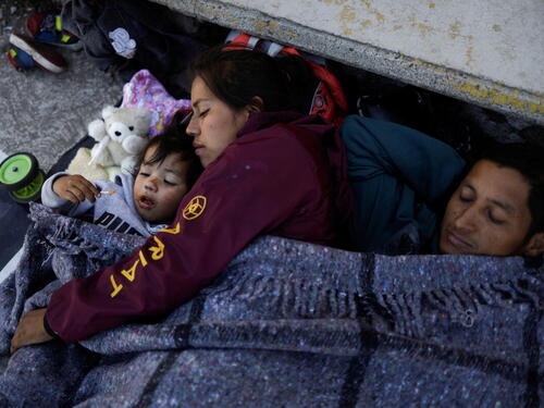 A family rests in the Mexican city of Rio Frio de Juarezas as they journey towards Mexico City, on 11 December