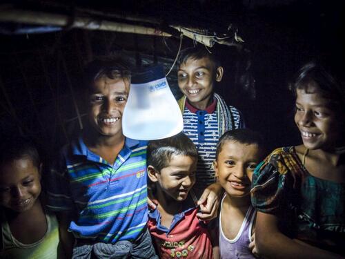 Rohingya children sit beneath a solar lantern.