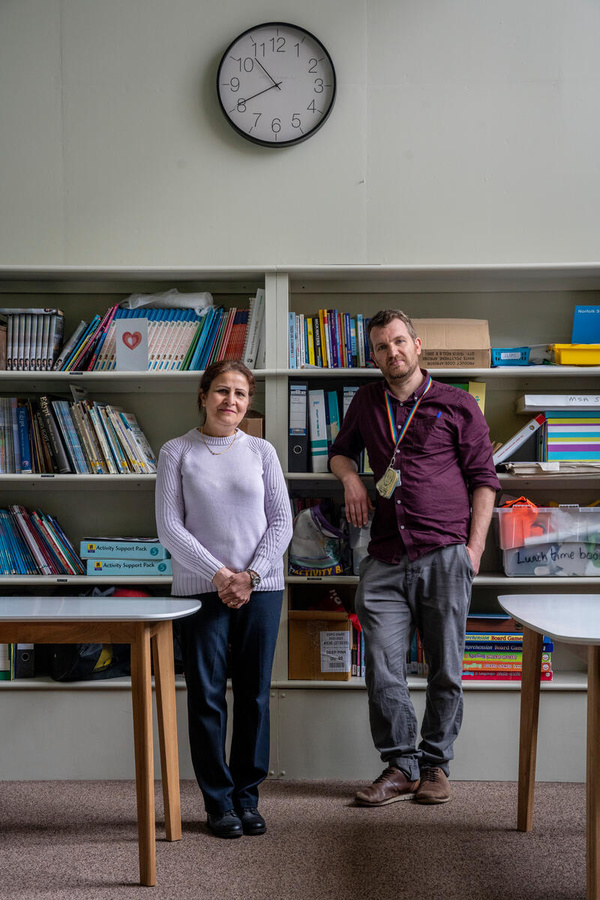 A woman and a man both stand in a classroom looking at the camera.