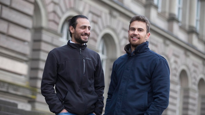 Two men stand next to each other and laugh