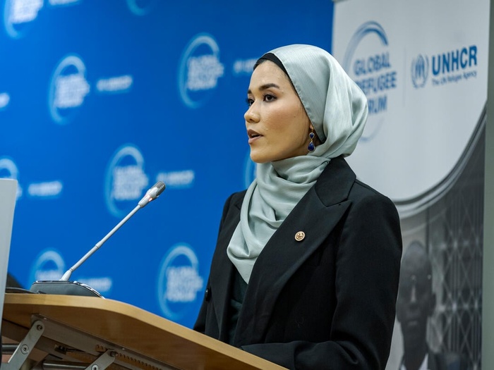 Masomah speaks into a microphone on the stage of an event. 