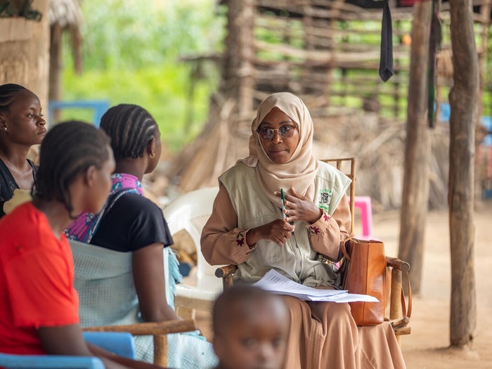 A group of women sit on chairs and discuss.