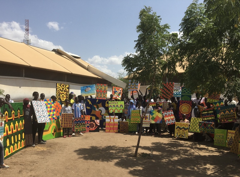 A group of people pose outside with abstract paintings 