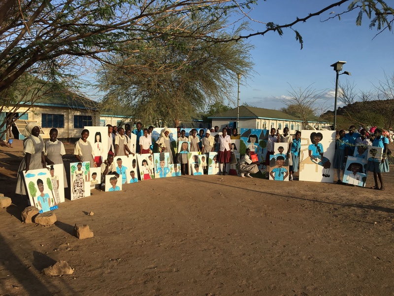 A group of people stand in a semi circle with their large scale portraits 