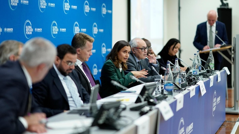Several speakers sit behind a long panel table with GRF branding. 