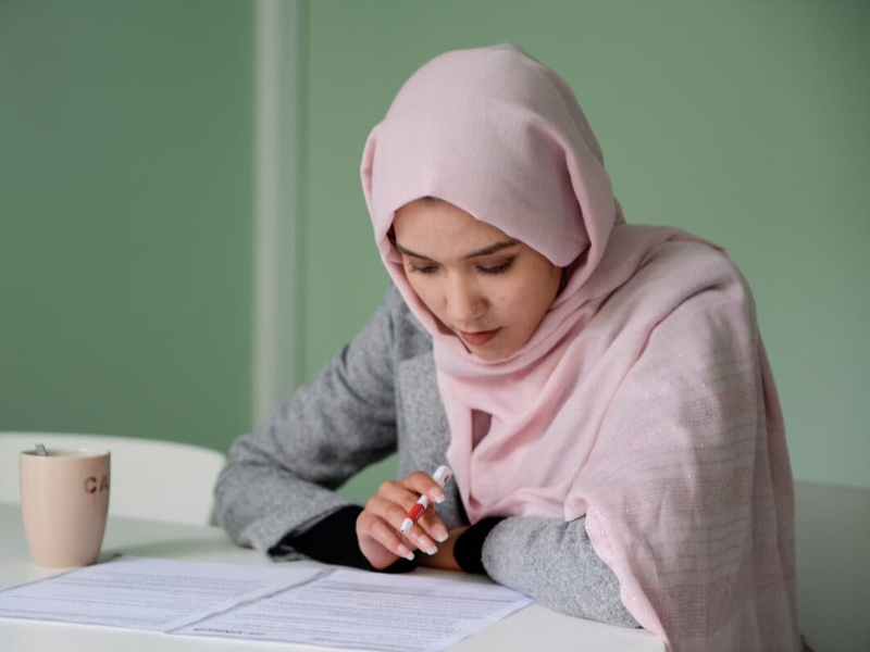Masomah studying at a desk in a classroom.