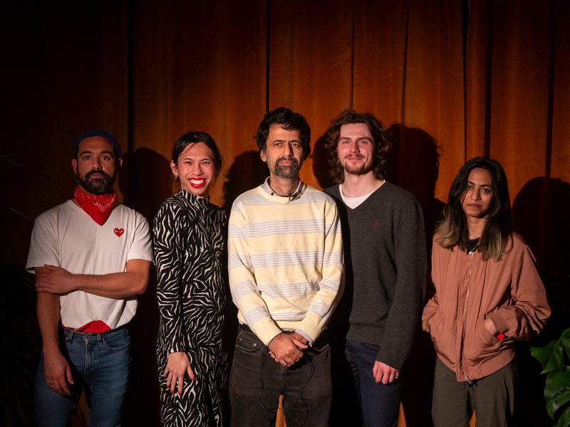 5 people pose for a photo in front of a brown curtain