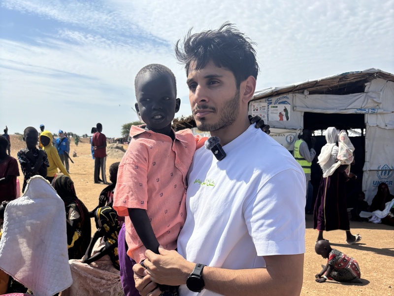 Omar carrying a young child in his arms