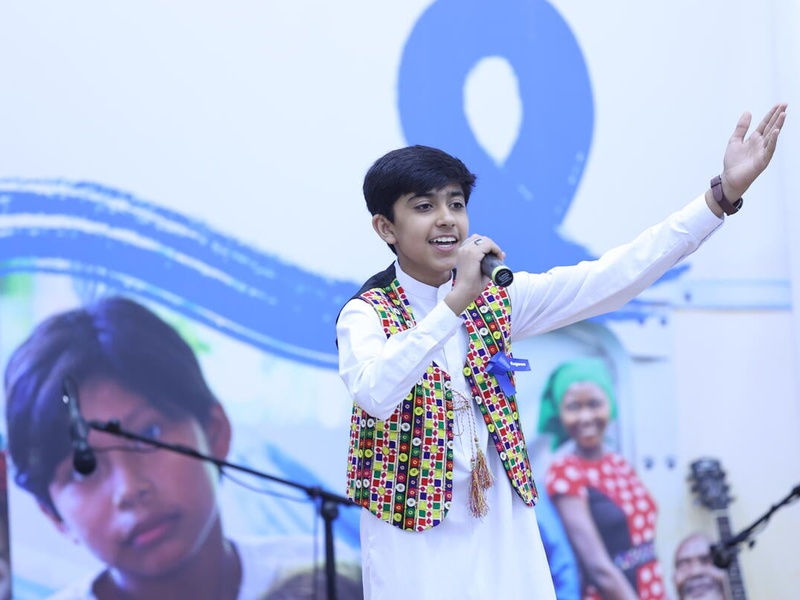 A young boy singing on stage