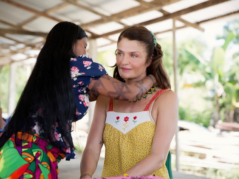 Floriselda Chamapuro putting jewely around Helena Christensen's neck