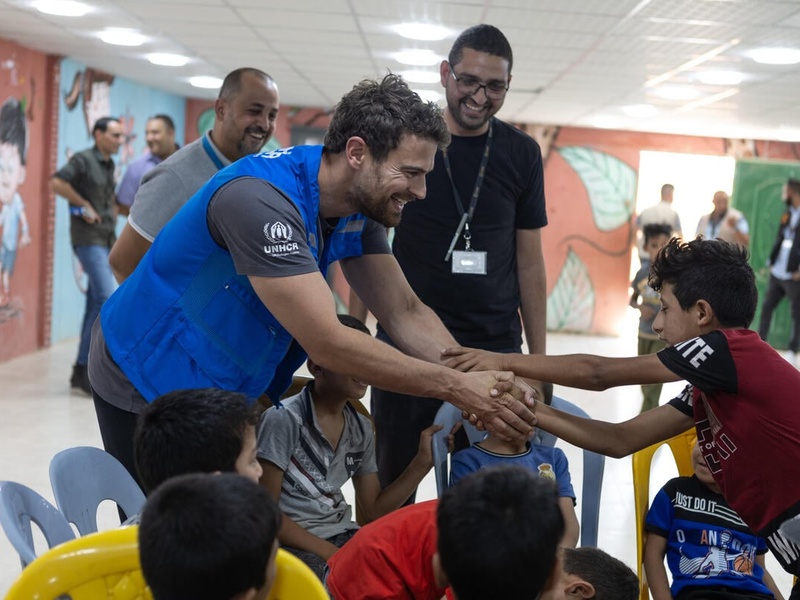 Theo James smiles and holds the hands of a young boy