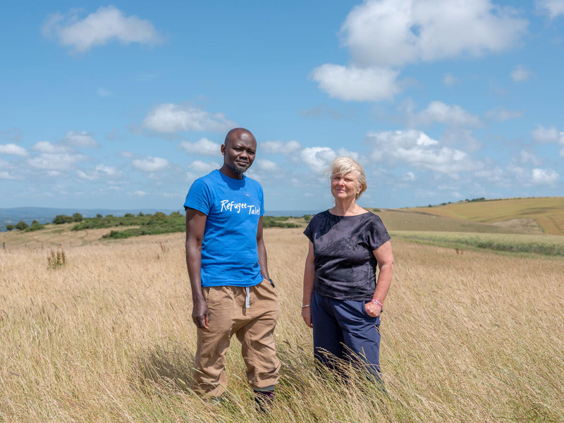 Man and woman pose in a windy field.