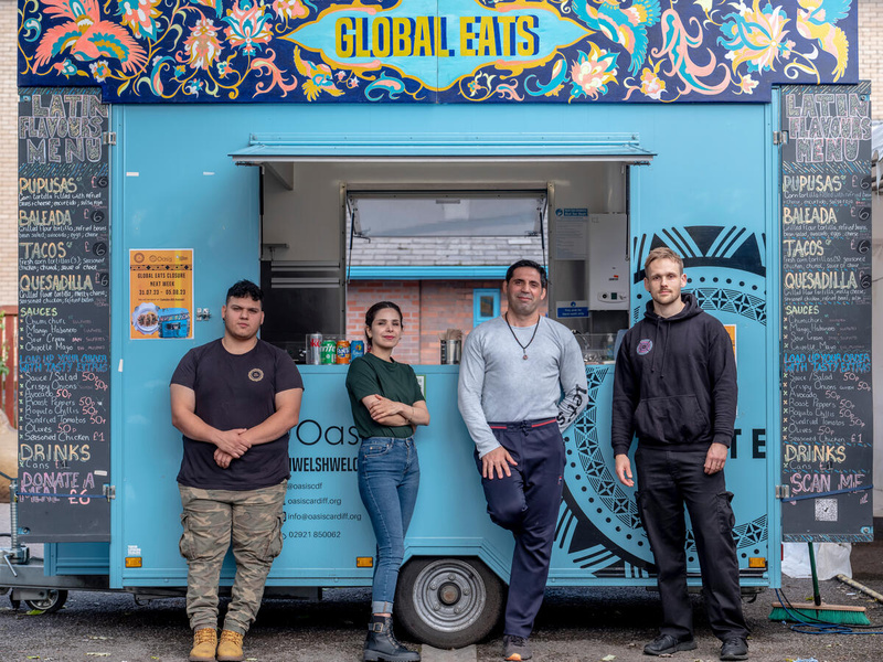 Four people pose in front of a food truck.