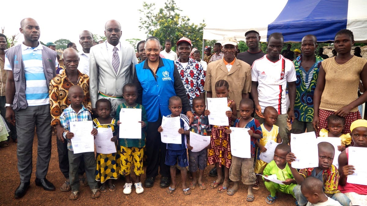 Barbara Hendricks stands with children holding their birth certificates.