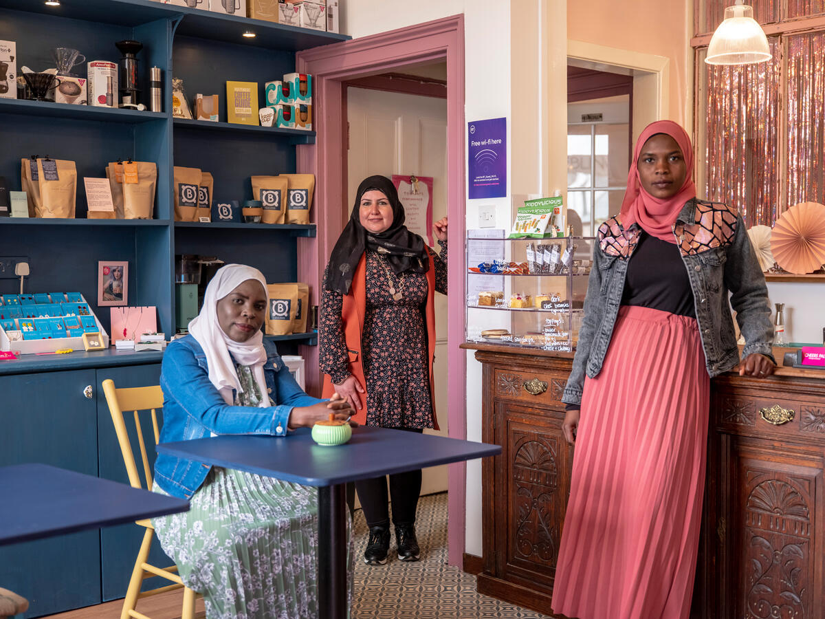 Three women pose for photo in a café.