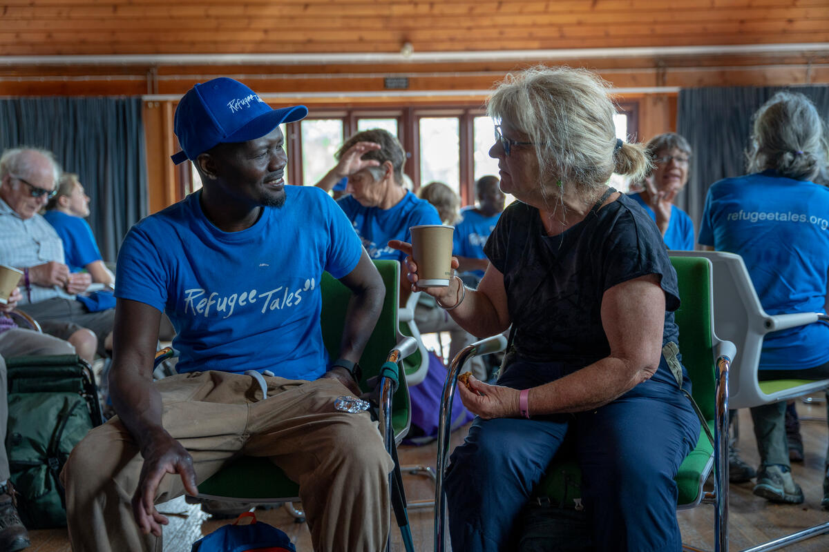 Man and woman chat over coffee in a community hall.