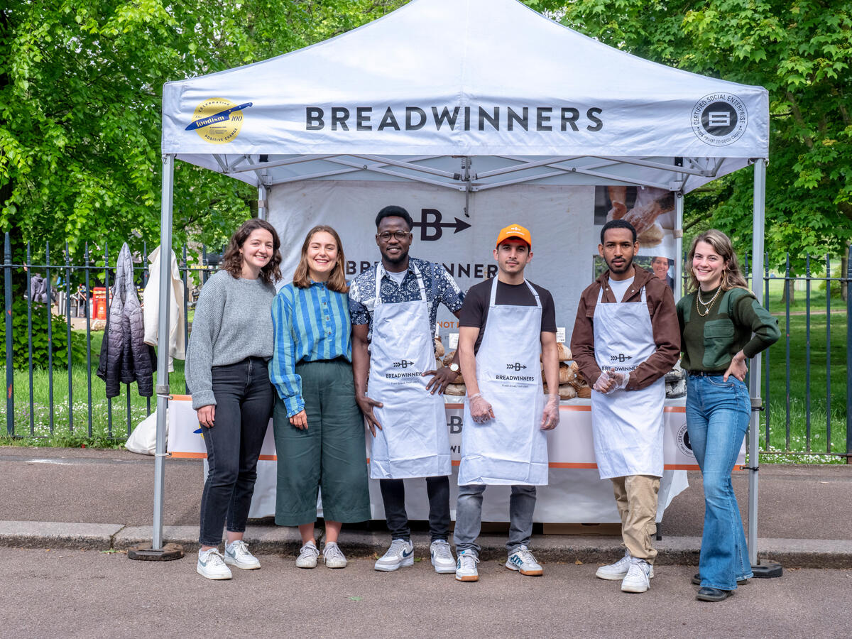 Six people pose in front of a market stall.