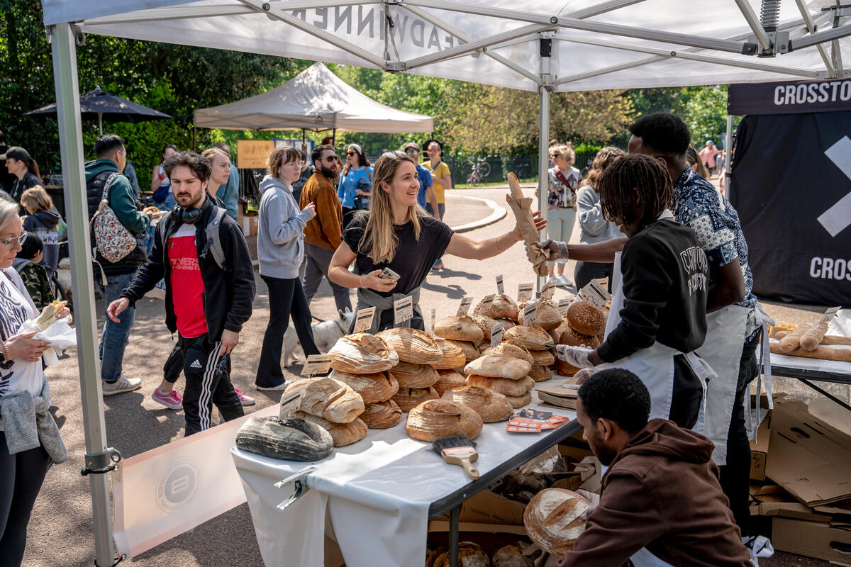 In a market stall, a woman buys bread.
