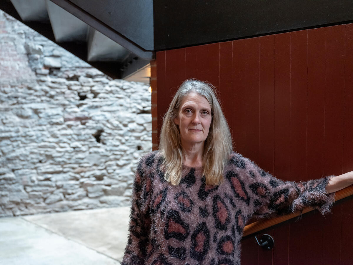 A woman poses in front of a red wall.