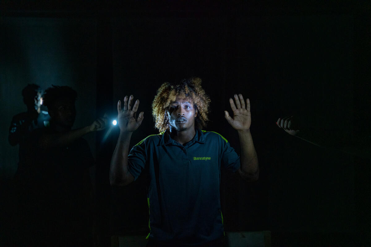 A mans face lit up by a torch.