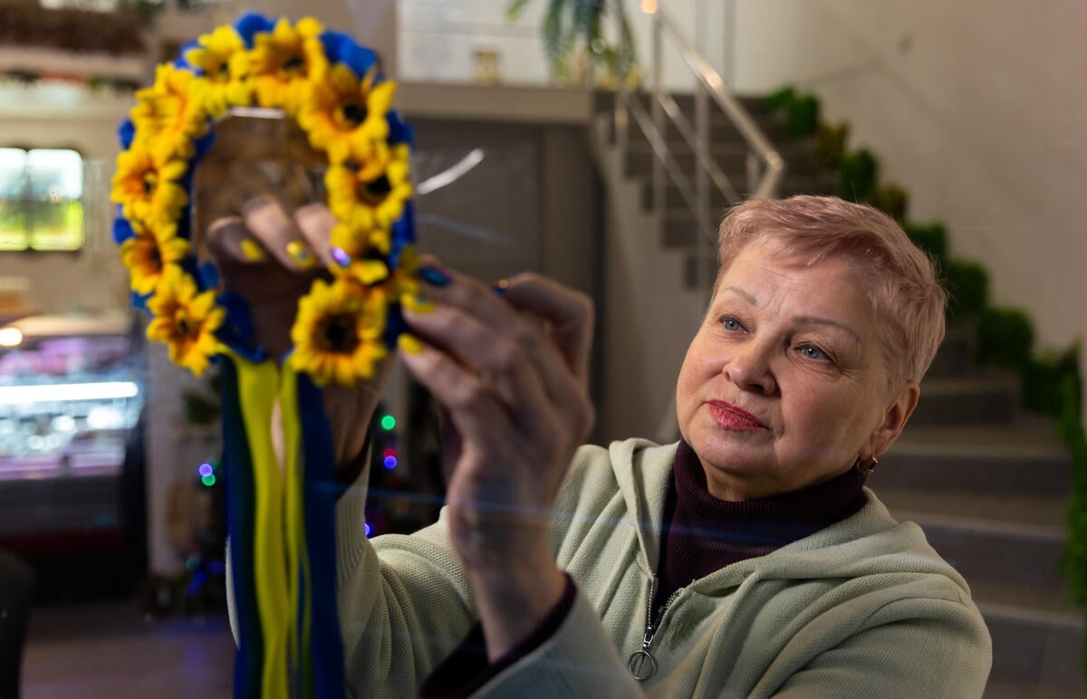 A woman holds up a wreath of flowers in Ukrainian colors