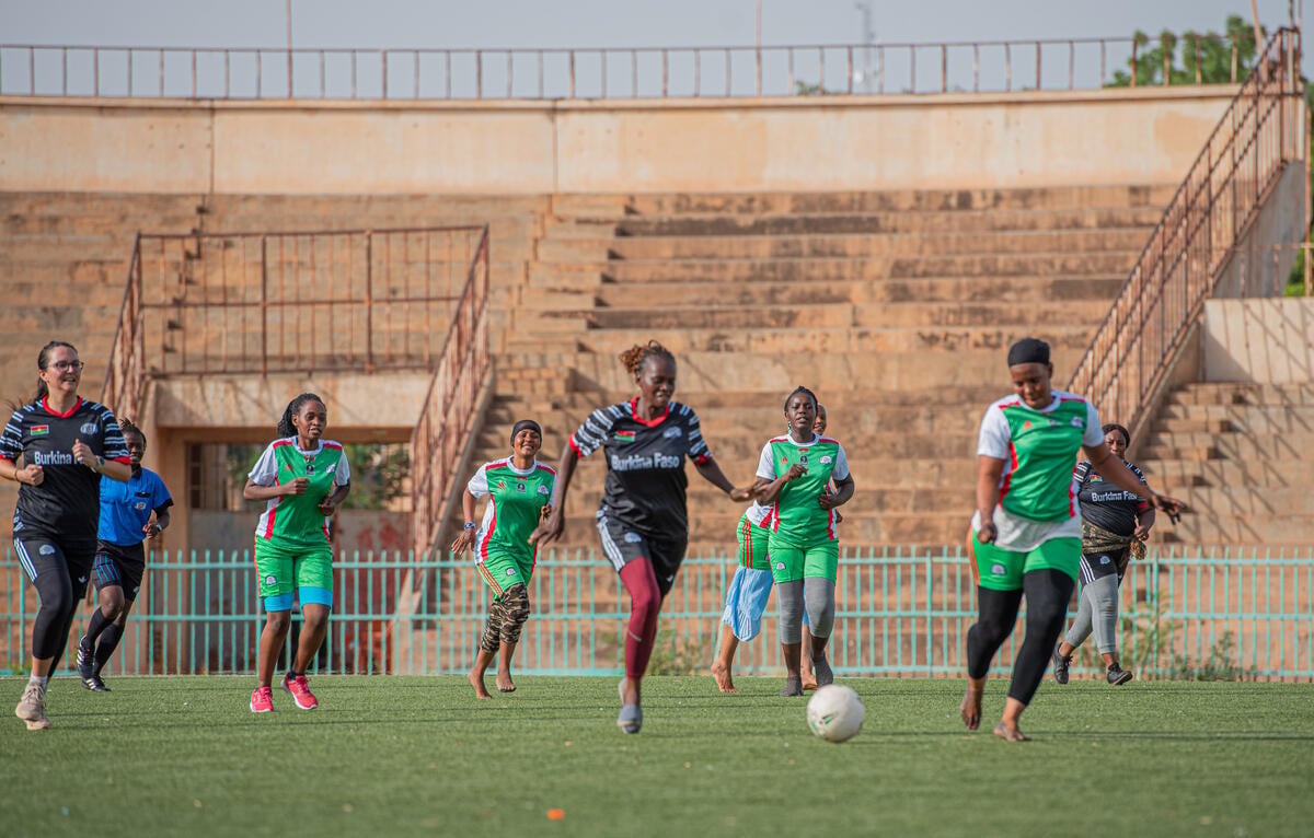 A group of people play football in an outdoor stadium