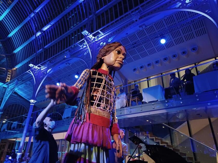 Little Amal arrived in the UK in October 2021. At an evening hosted by the Royal Opera House, London, she was helped to sleep by performers from The Royal Opera House Chorus, Phosphorus Theatre, Citizens of the World Choir and The Royal Ballet.