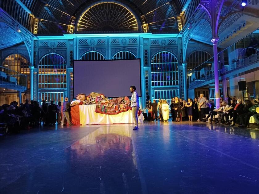 Little Amal arrived in the UK in October 2021. At an evening hosted by the Royal Opera House, London, she was helped to sleep by performers from The Royal Opera House Chorus, Phosphorus Theatre, Citizens of the World Choir and The Royal Ballet.