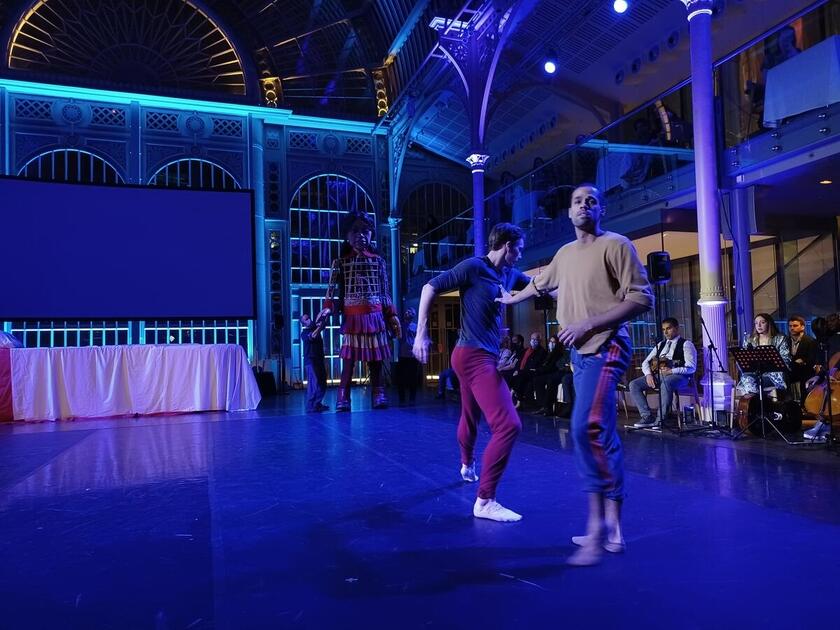 Little Amal arrived in the UK in October 2021. At an evening hosted by the Royal Opera House, London, she was helped to sleep by performers from The Royal Opera House Chorus, Phosphorus Theatre, Citizens of the World Choir and The Royal Ballet.