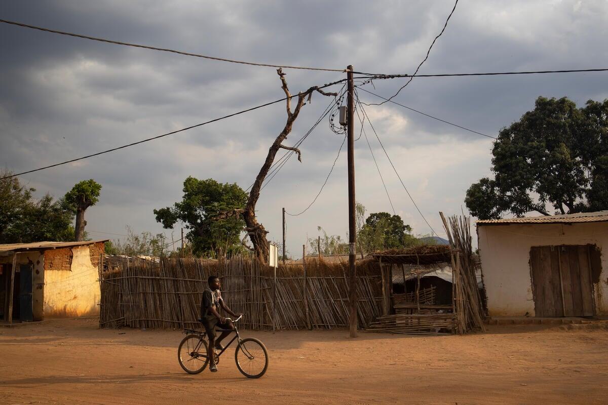 Un hombre pasea en bicicleta cerca de un poste de electricidad en el asentamiento de Marratane, donde viven alrededor de 9.200 personas refugiadas, principalmente de la República Democrática del Congo y Burundi.
